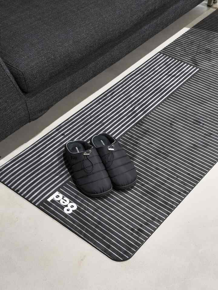 Black and gray tone balcony space featuring striped rug, sofa, and slippers with a modern atmosphere