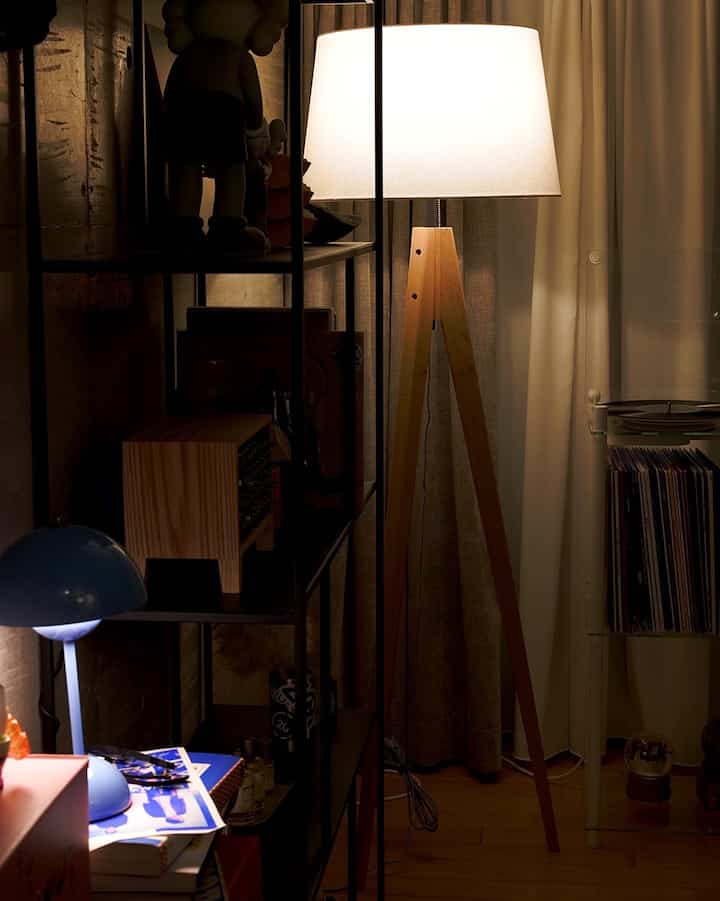 暖かい木目調のモダンな一人暮らしの空間、フロアランプと本棚、カーテンが配された落ち着いた雰囲気のインテリア