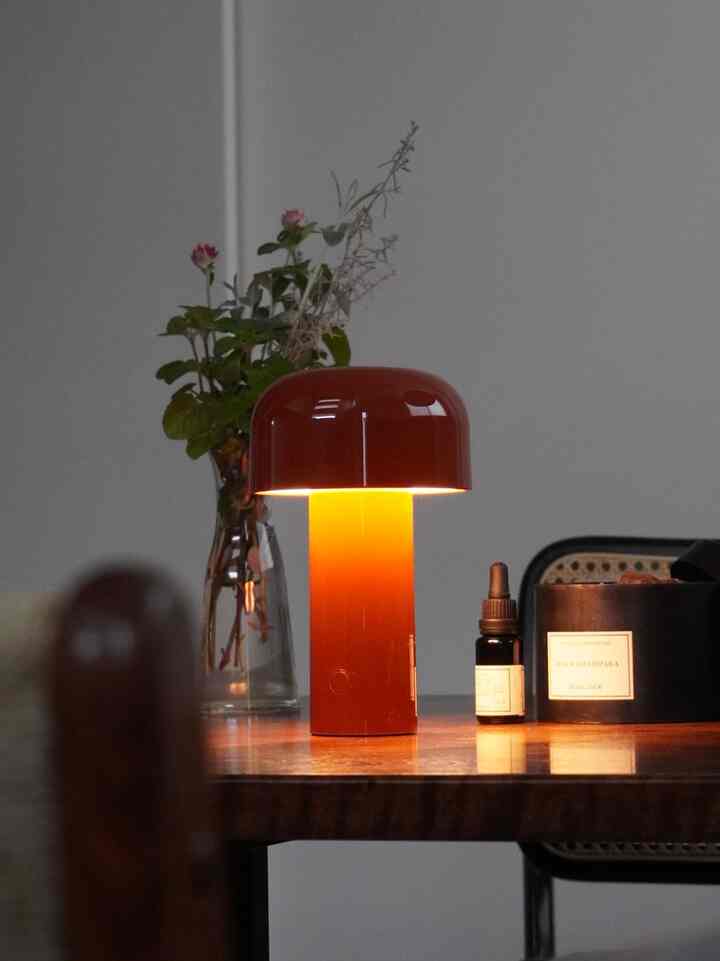 温かみのあるオレンジ色のテーブルランプと自然の植物、ディフューザーが配置されたナチュラルなキッチンスペース