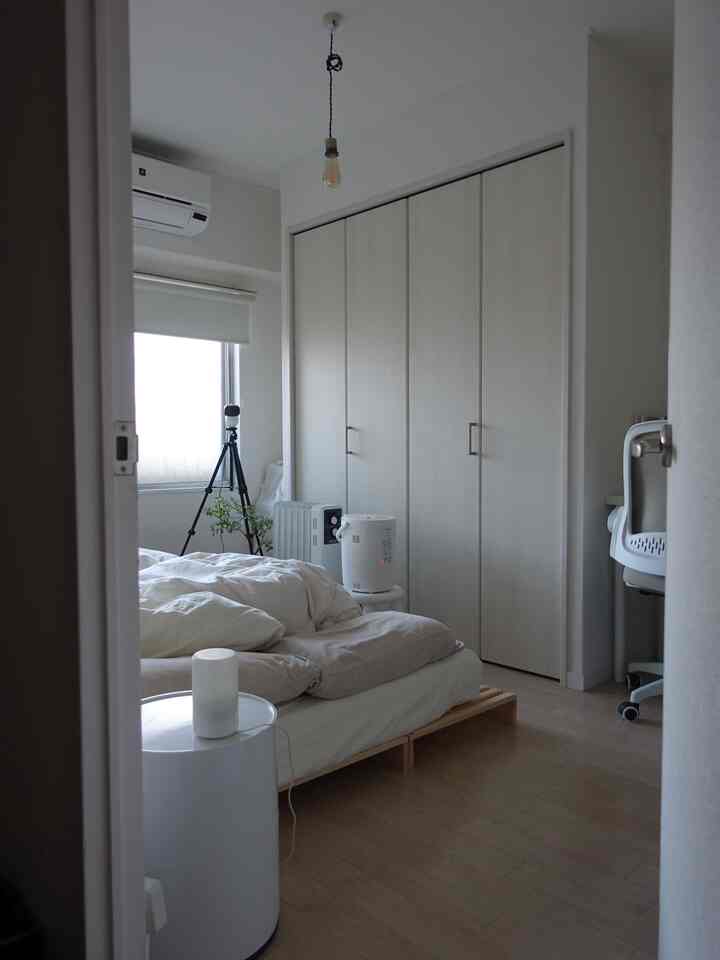 明るいホワイトとナチュラルウッドトーンの一人暮らし用寝室、パレットベッドとナイトテーブルが配置されたコンパクトな空間