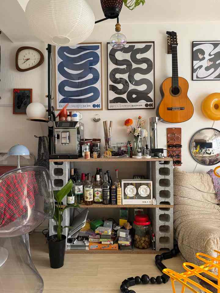 Beige sofa and Mid-Century Modern art posters decorate a cozy studio apartment home bar area
