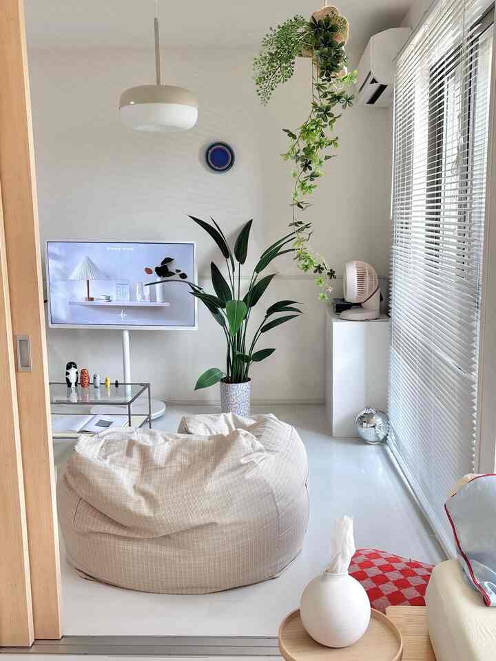 白とナチュラルトーンのリビング、中央にビーズクッションとテレビ台が配置された落ち着いた空間