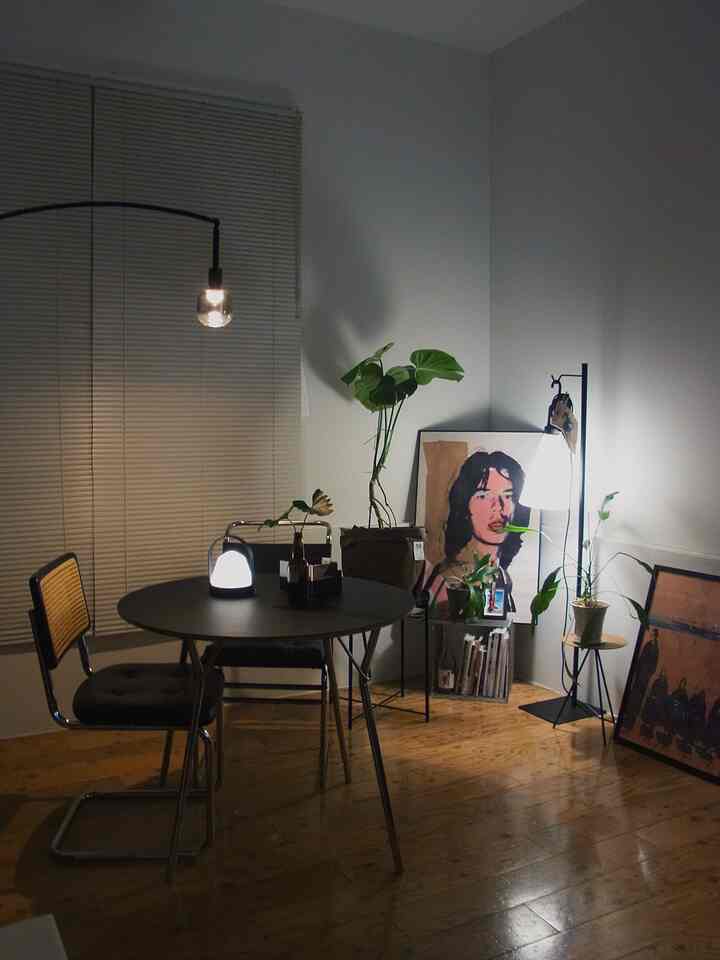 モノトーンとウッド調が調和したダイニング、シンプルなテーブルと椅子、ポスターや植物が配置された温かみのあるインテリア