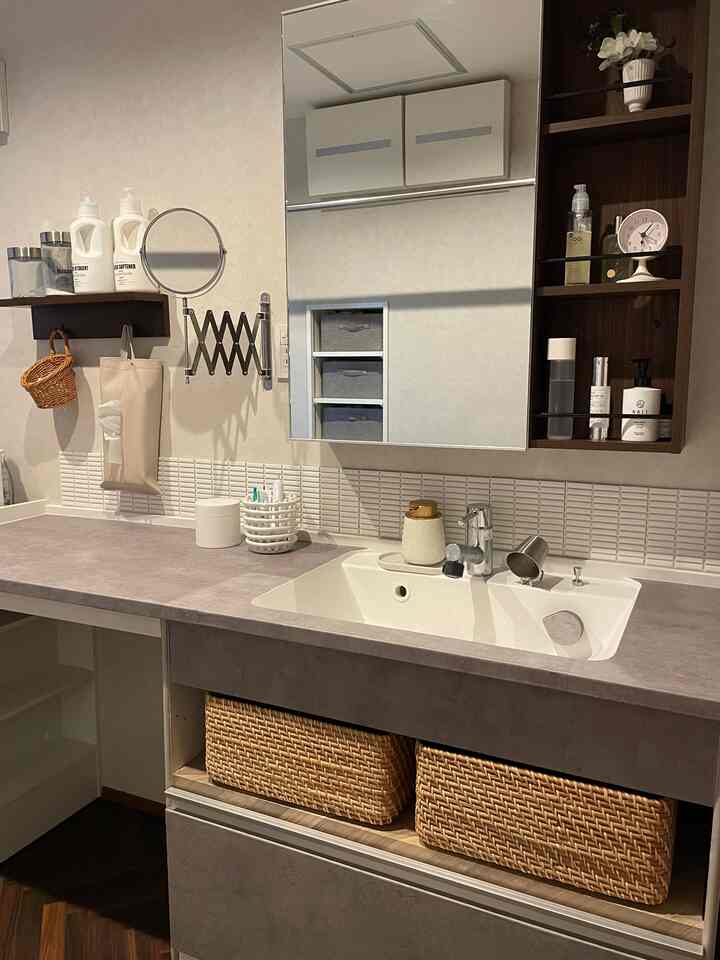 ベージュと白を基調とした浴室の洗面台、モダンなインテリアにラタン収納とリメイクシートが配置された清潔感のある空間