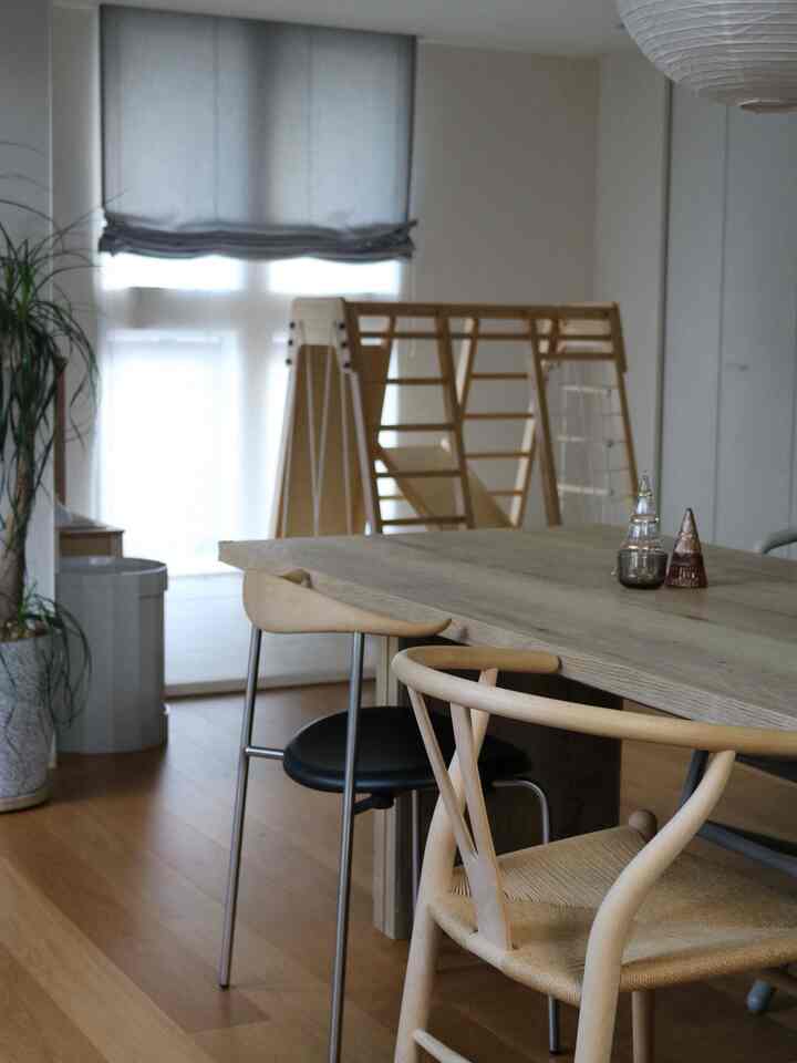 白い壁と木目調の家具が調和したダイニング、子供用の木製ジャングルジムが配置された温かみのある家族の空間