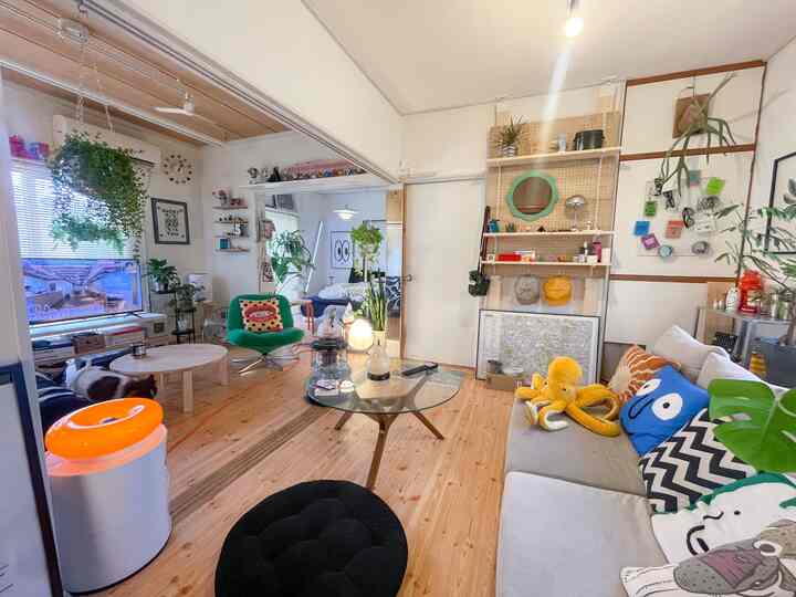 ナチュラルとグリーンの色調のリビング、グリーンのアームチェアとオープンシェルフ、間接照明が居心地の良い雰囲気を作る空間