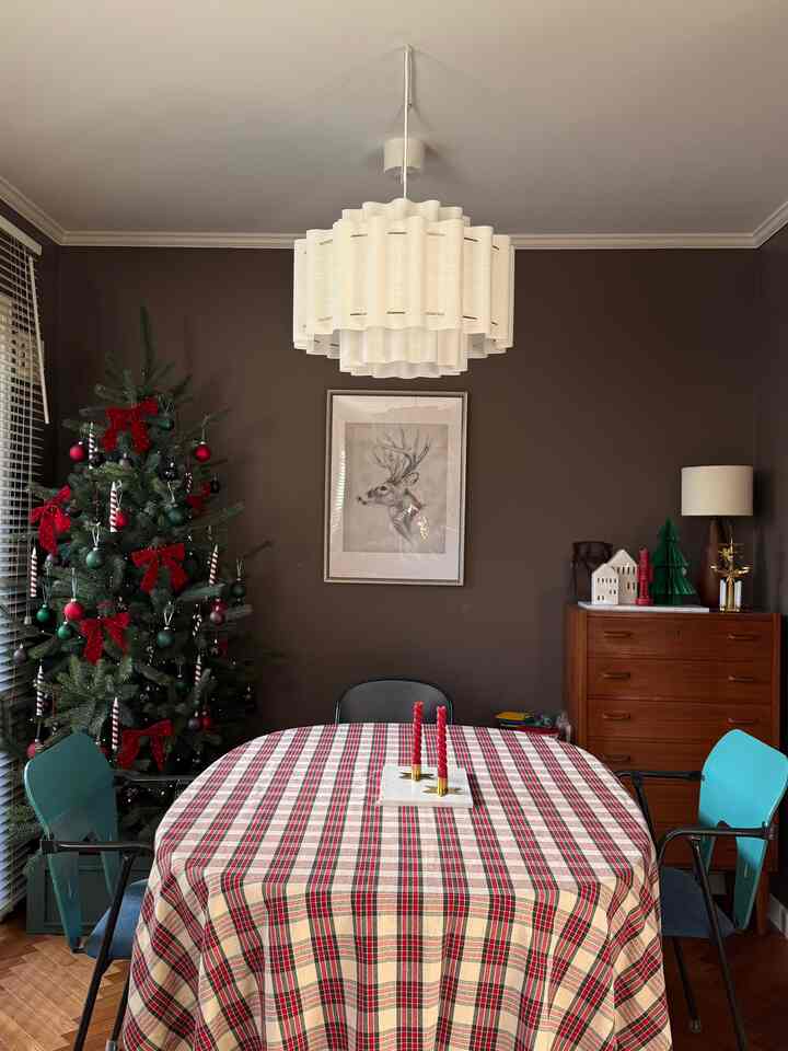 ブラウンの壁と赤いチェックのテーブルクロスが印象的なダイニング、クリスマスツリーと温かみのある照明が配置された雰囲気のあるインテリア