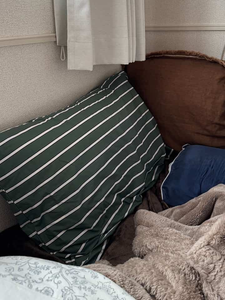 ベージュとブラウンのトーンの寝室の一角、多彩な色の枕とブランケットが置かれた雰囲気のある空間