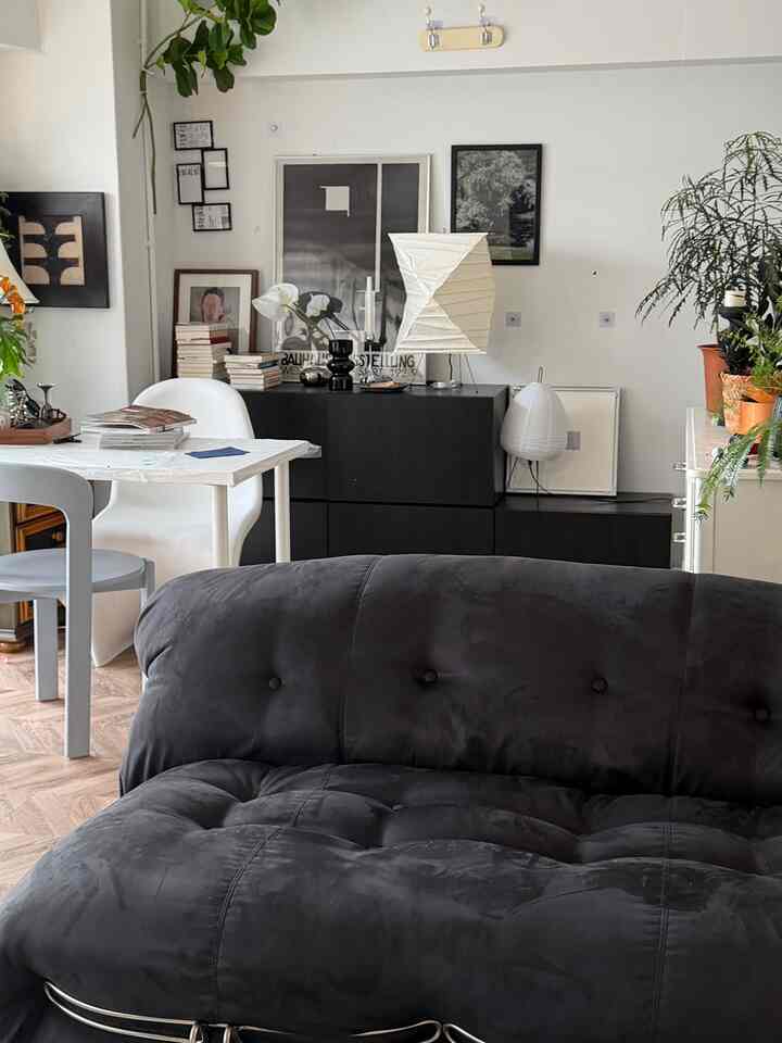 White and black toned living room featuring a sofa, dining table, floor lamps, and plants in a modern natural style