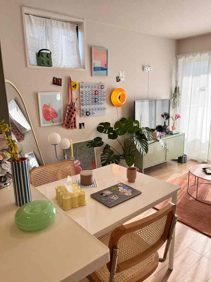 Bright white and beige toned living and dining room with natural furniture and a large leafy plant creating a cozy atmosphere