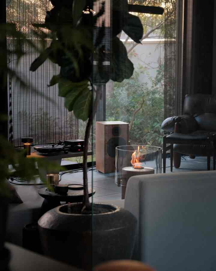 ナチュラルな色調のリビング、サイドテーブルとヴィンテージオーディオ機器、室内暖炉がある雰囲気のあるインテリア