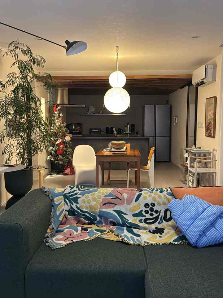 Wood tone and white living-dining space featuring sofa and pendant lights creating a cozy interior