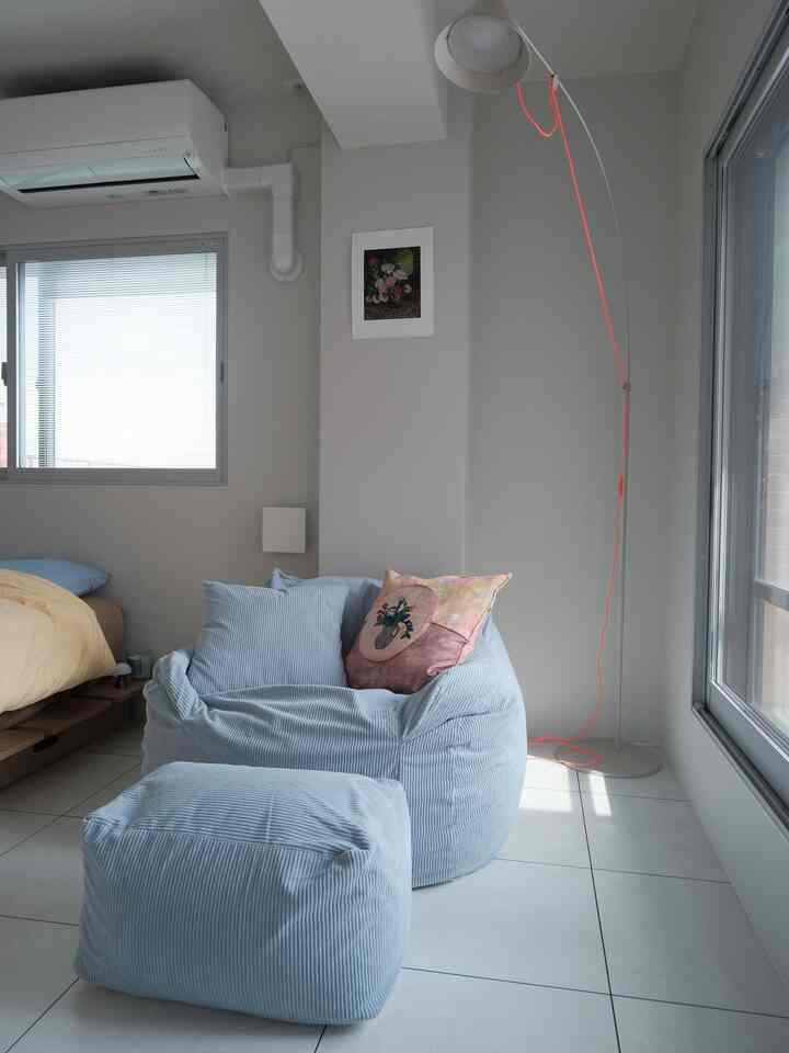 Cozy bedroom featuring soft blue bean bag chair and a bed with yellow duvet in a softly lit space
