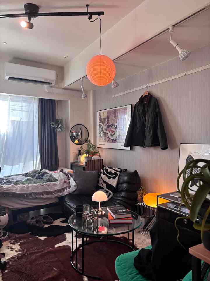 暖かいオレンジ色の照明とモダンな家具が配置された8畳サイズの一人暮らし用リビングスペース