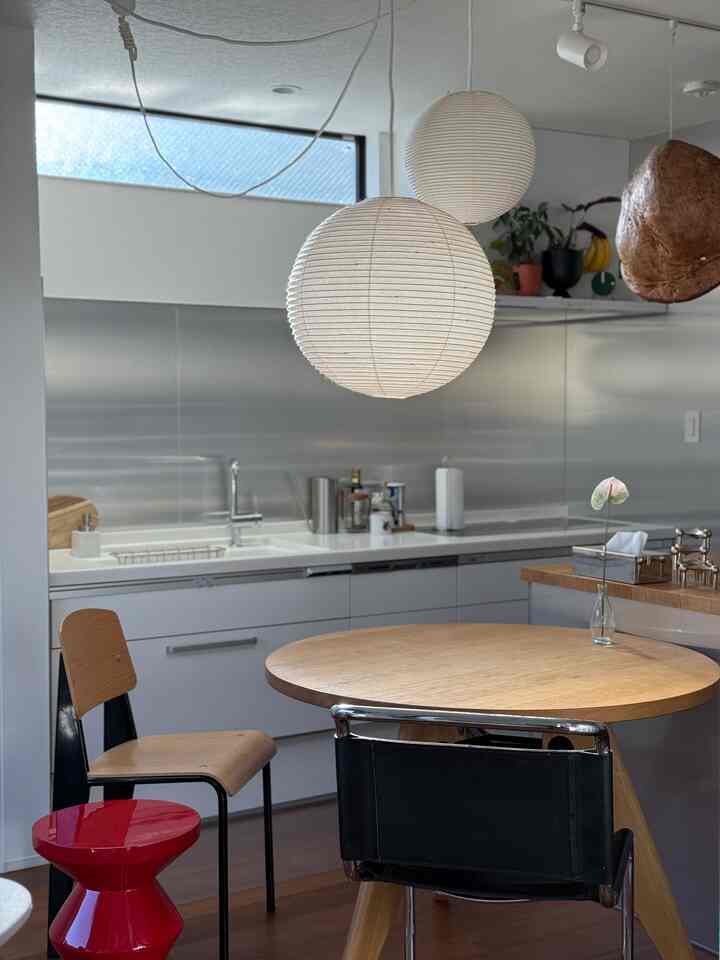 A white and wood tone dining room featuring mid-century modern furniture and pendant lights with a clean, cozy atmosphere