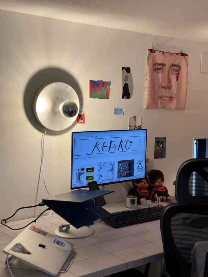 White-toned home office with a silver wall sconce and modern desk setup creating a clean workspace atmosphere