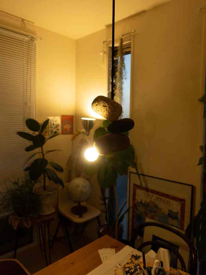 暖かい木目調とペンダントライト、植物が配置されたミッドセンチュリーモダンスタイルの落ち着いたリビング空間