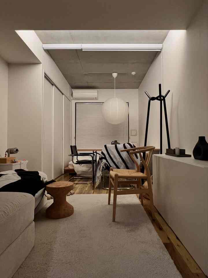 白と木目調が調和した、一人暮らし向けのソファとダイニングが配置されたミニマルで自然な雰囲気のインテリア