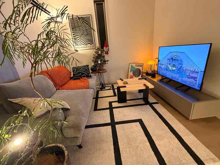 温かみのあるベージュとウッドトーンの1LDKリビング、グレーのソファと木製コーヒーテーブル、間接照明が調和した印象的な空間