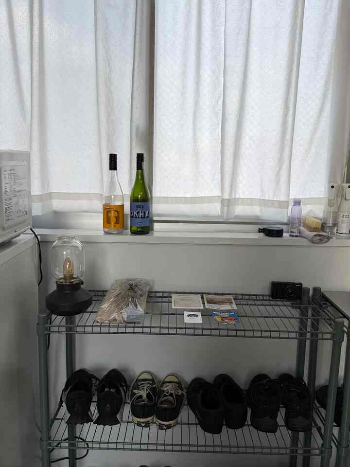 白いカーテンとグレーのシューズラックが配置された清潔感のある玄関の空間