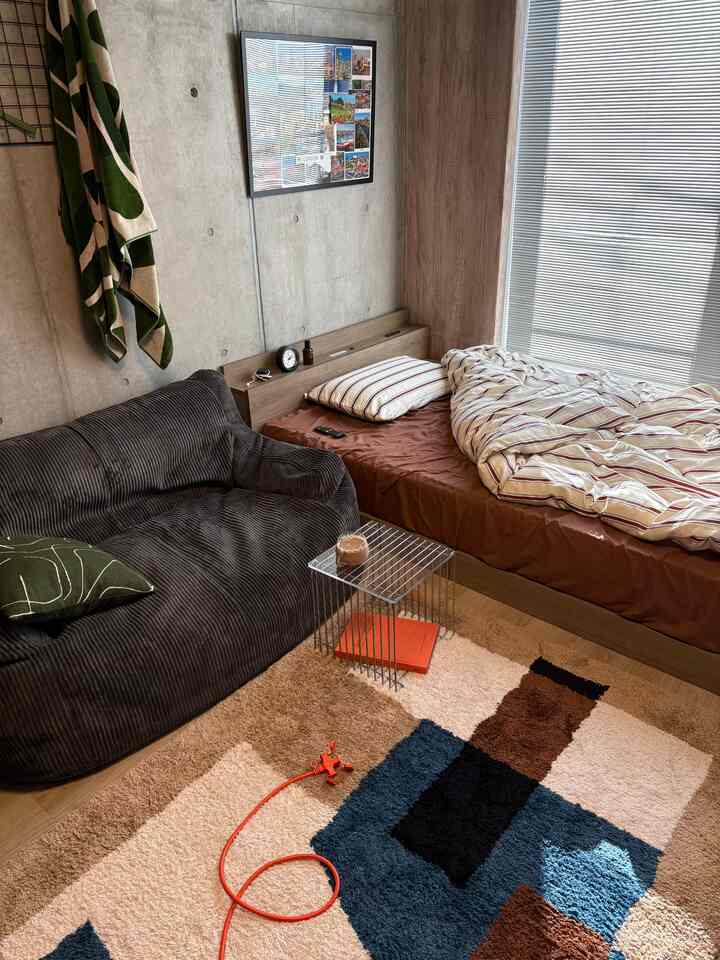 Brown and gray toned 1K bedroom featuring a large bean bag sofa and bed with a cozy atmosphere