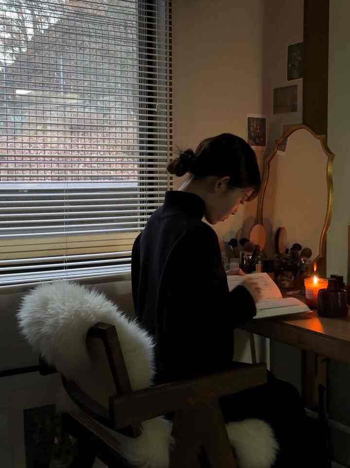 Warm wood tones in a cozy dark-toned home office, showing a person reading at a desk by candlelight
