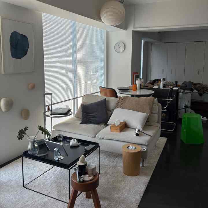 白とブラウンのトーンのナチュラルモダンなリビング、ベージュのソファとブラックのコーヒーテーブル、大きな窓とペンダントライトが配置された印象的な空間