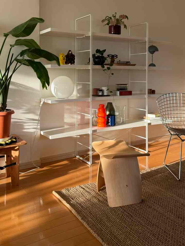 ナチュラルな木目調とホワイトの調和が美しいリビング、木製のバタフライスツールと植物が配置された温かみのある空間