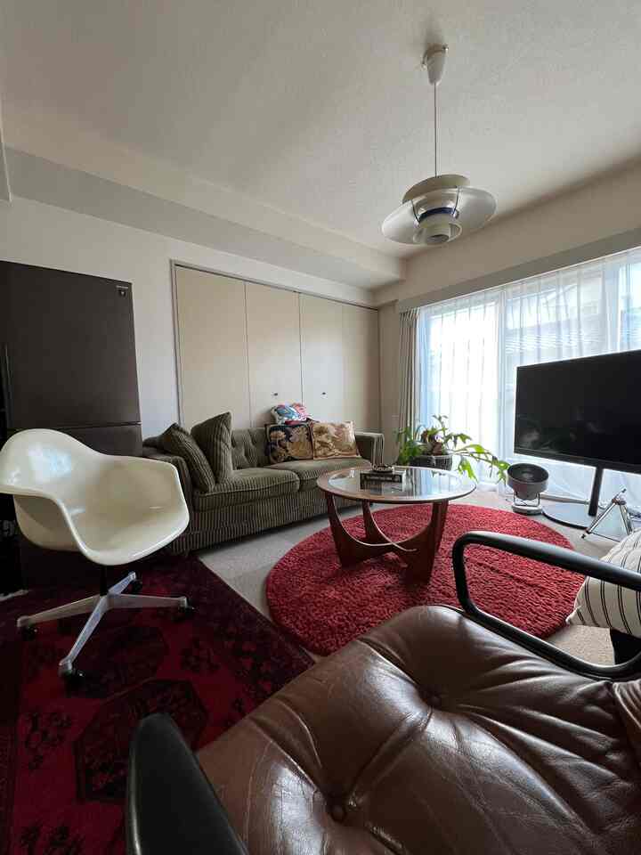 赤と茶色のトーンが特徴のワンルームリビング、ミッドセンチュリーモダン家具とペンダントライトが配置された温かみのある空間