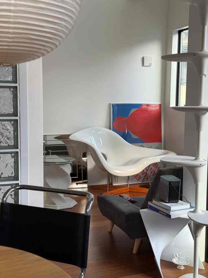 白を基調としたリビング、ミッドセンチュリーモダンの椅子とキャットタワーが配置された雰囲気のある空間