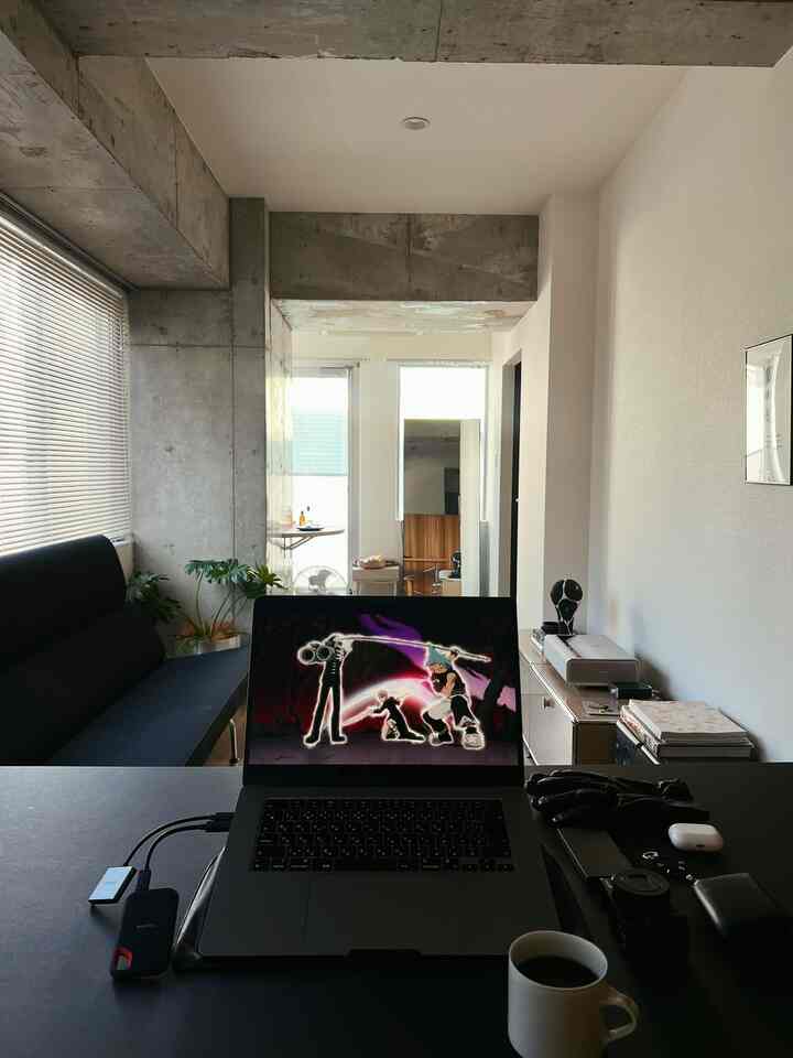 モダンなコンクリート壁と黒いソファ、植物と電子機器が配置されたコンパクトなリビングルーム