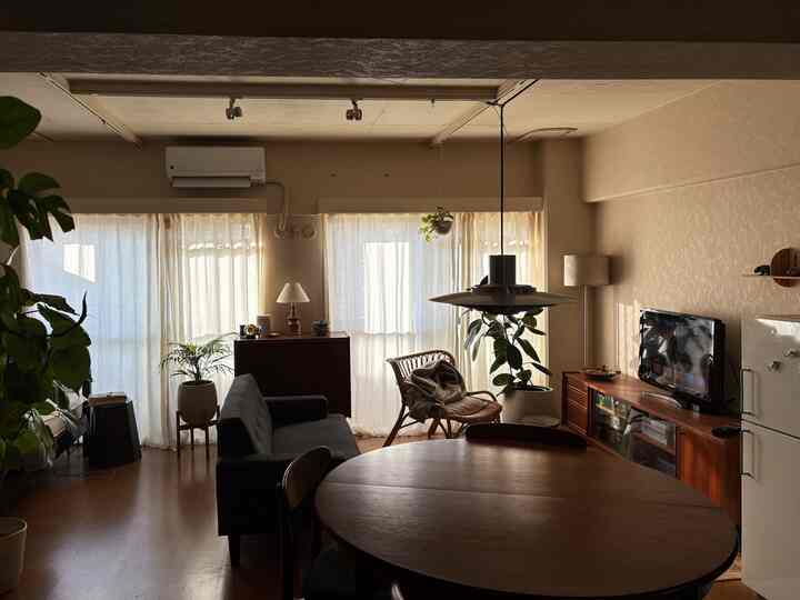 Warm brown tone natural vintage living room featuring a large dining table, sofa, and plants creating a cozy atmosphere