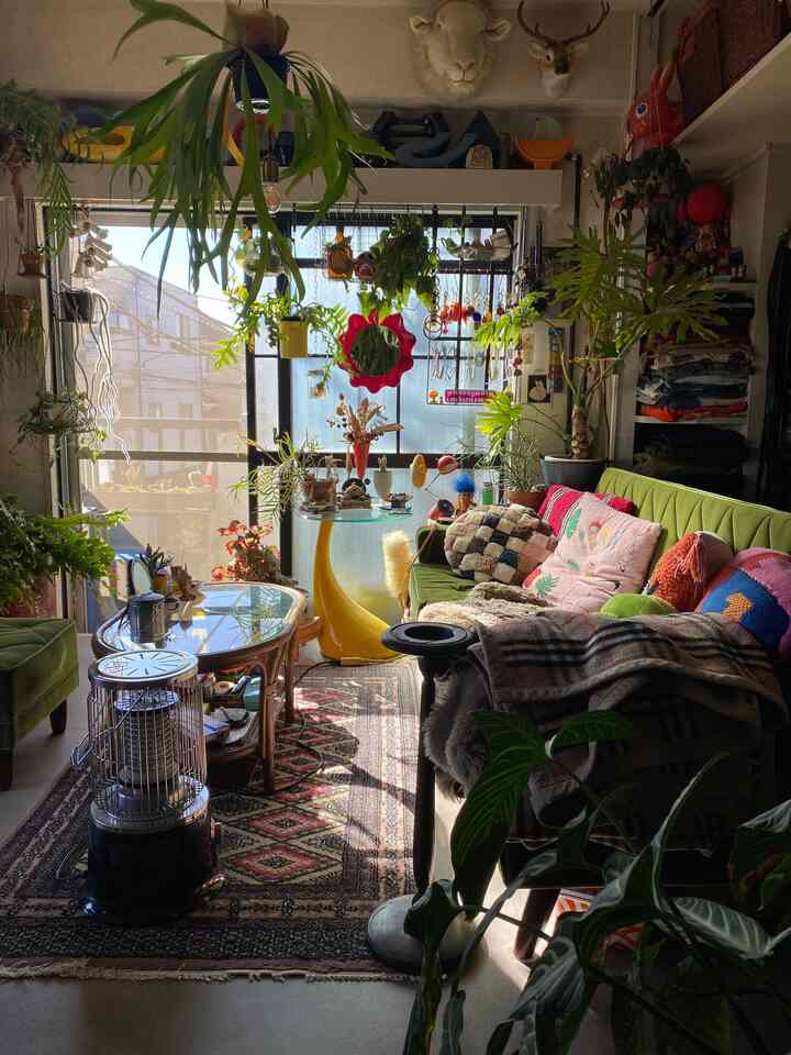 緑色が際立つリビング、ミッドセンチュリーモダンのソファと多彩な観葉植物が配置された雰囲気のあるヴィンテージ空間