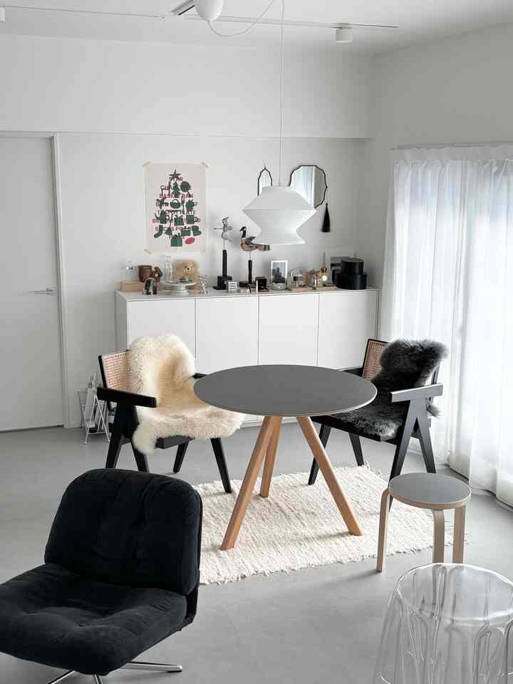 Natural modern dining room with ivory rug under a round dining table and black armchairs, creating a clean and soft atmosphere