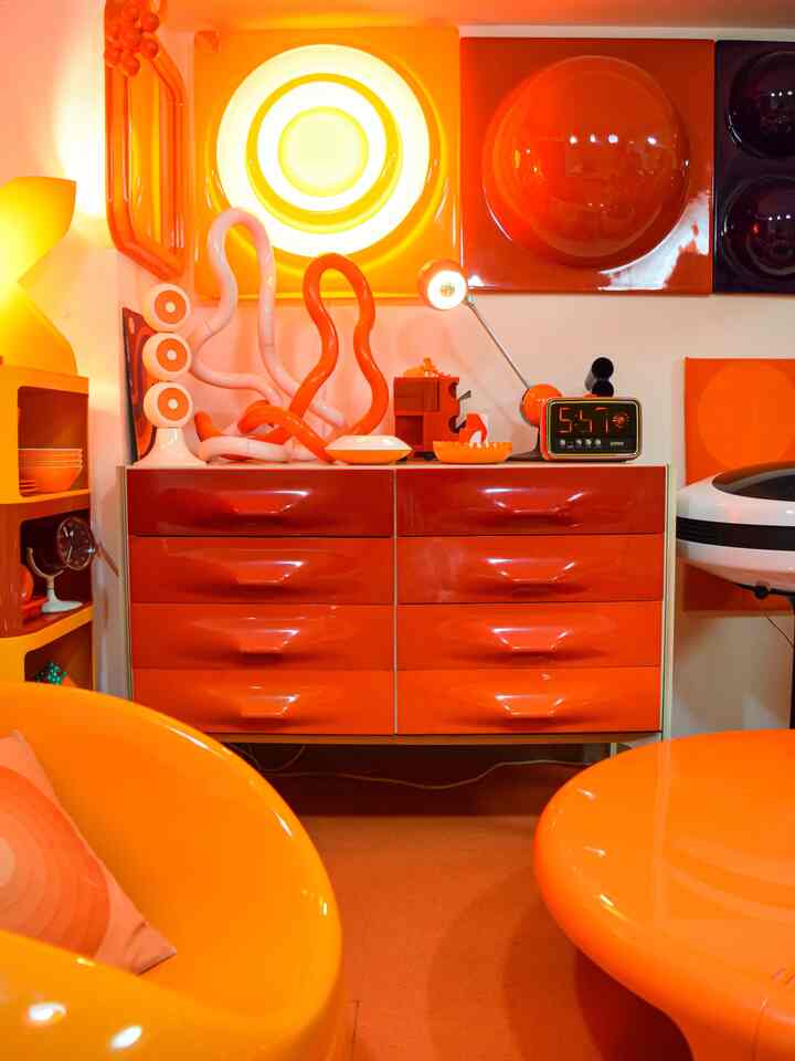 Vivid orange-toned living room featuring retro cabinet and distinctive curved furniture with a bright atmosphere