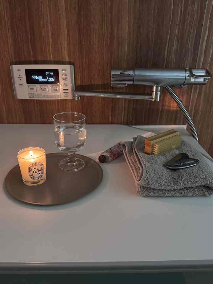 温かみのある色調のバスルーム、タオルやキャンドル、浴用ブラシと水のグラスが配置された雰囲気のあるインテリア