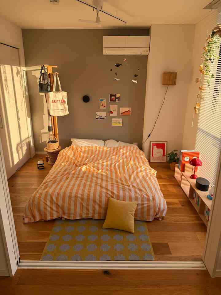 Warm beige and brown toned bedroom featuring a centrally placed bed with orange striped duvet cover, creating a cozy atmosphere.