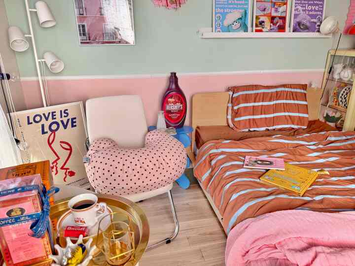 A compact bedroom with pink and brown tones featuring a chair, bed, and home cafe accessories in harmonious setting