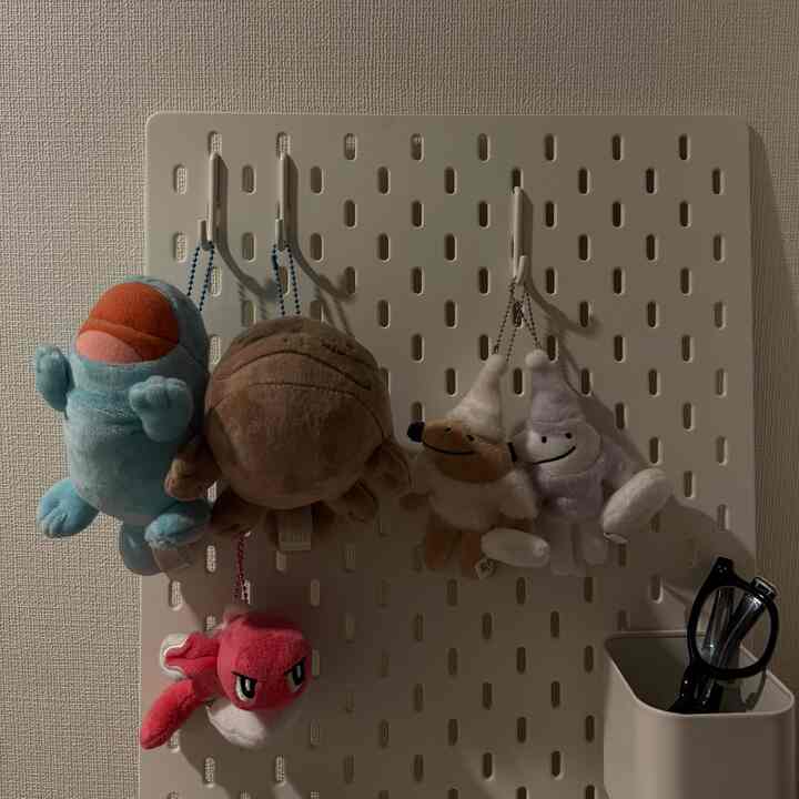 White-toned Skadis pegboard featuring cute plush toys hanging, a decorative and functional wall space