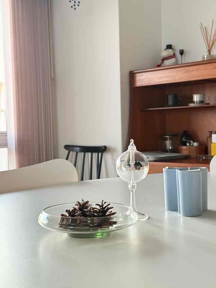 ホワイトと木目調が調和したダイニング、テーブルにガラスの器とキャンドルが置かれた落ち着いた空間