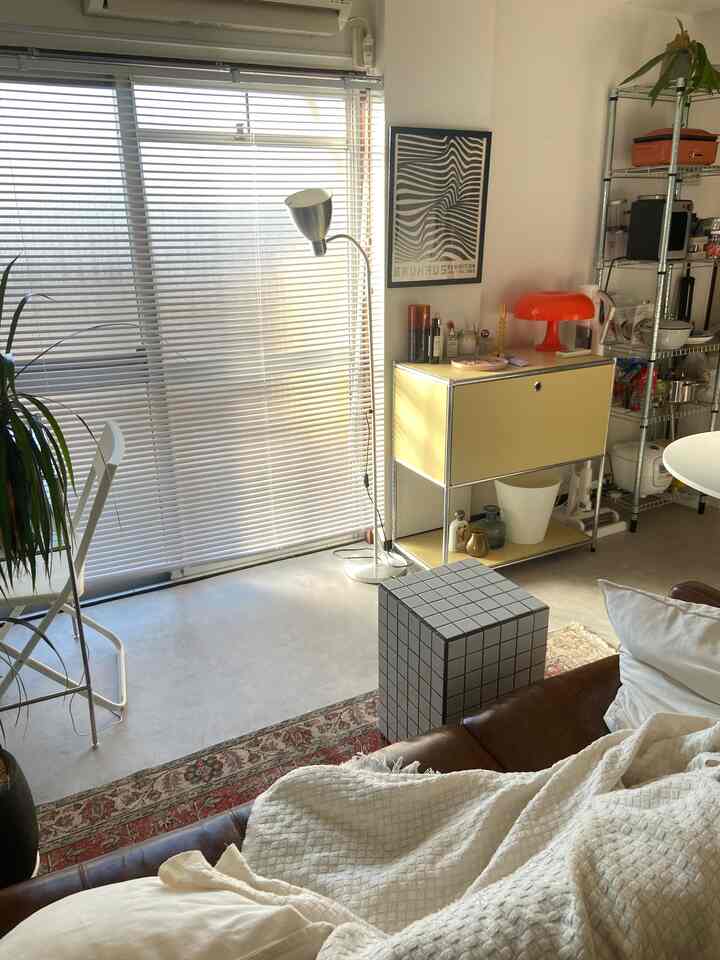 明るいホワイトとブラウンの1DKリビング、ミッドセンチュリーモダン家具とスツール、フロアランプが配置された落ち着いた雰囲気の空間