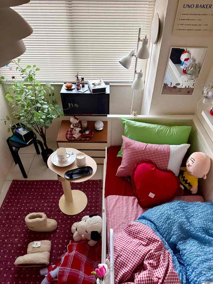 ホワイトとナチュラルトーンのコンパクトな一人暮らしの部屋、ベッドとスツール、植物が配置された温かみのある空間