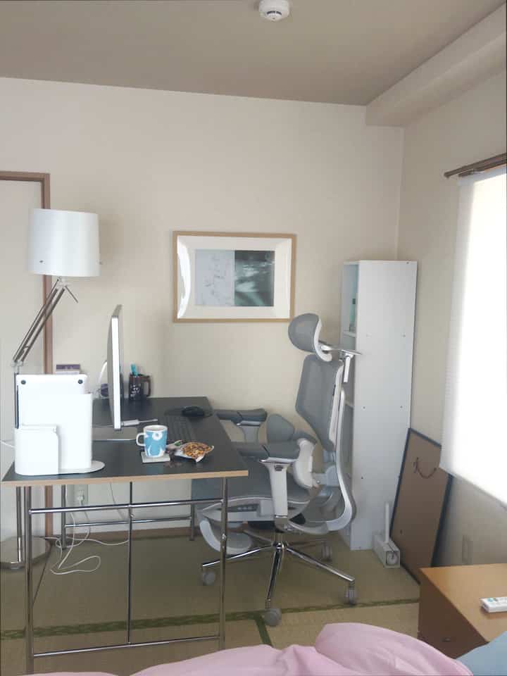 White and black toned studio apartment home office space featuring a desk and office chair, creating a calm remote work environment