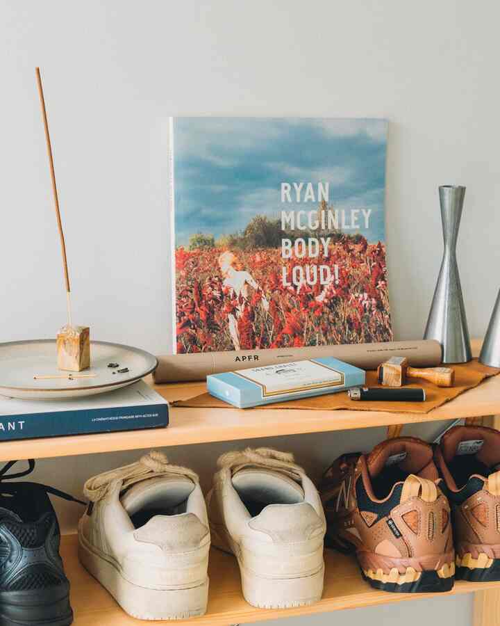 A simple, clean space featuring a natural color wood-toned shoe shelf with curated decorative objects