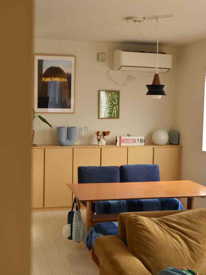 ナチュラルなブラウン色調と白い壁のダイニングルーム、木製のテーブルとブルーのベンチ、ブラウンのソファが配置されたモダンで落ち着いた雰囲気のインテリア