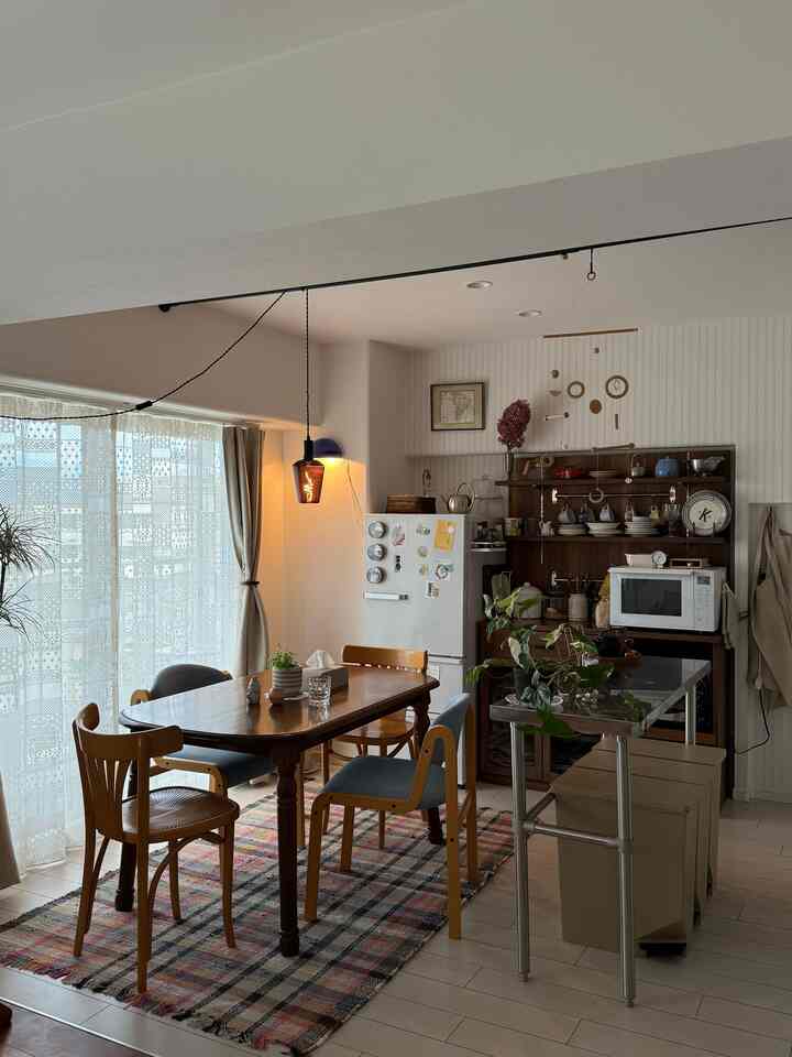 柔らかな白とブラウンの色調のダイニング、ヴィンテージのダイニングテーブルと椅子が配置された雰囲気のある空間