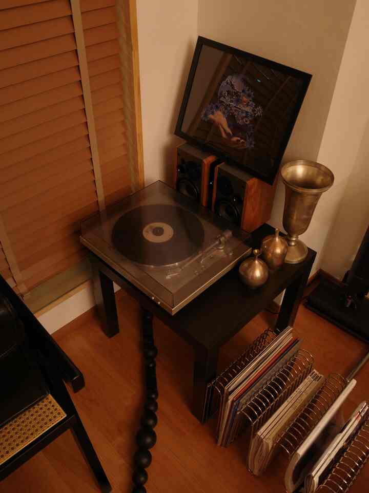 温かみのあるブラウンとブラックの色調の一人暮らし空間、ターンテーブルとスピーカーを配したミッドセンチュリーモダンのインテリア