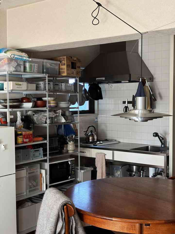 White and stainless steel kitchen featuring a wooden dining table and metal pendant light creating a cozy atmosphere