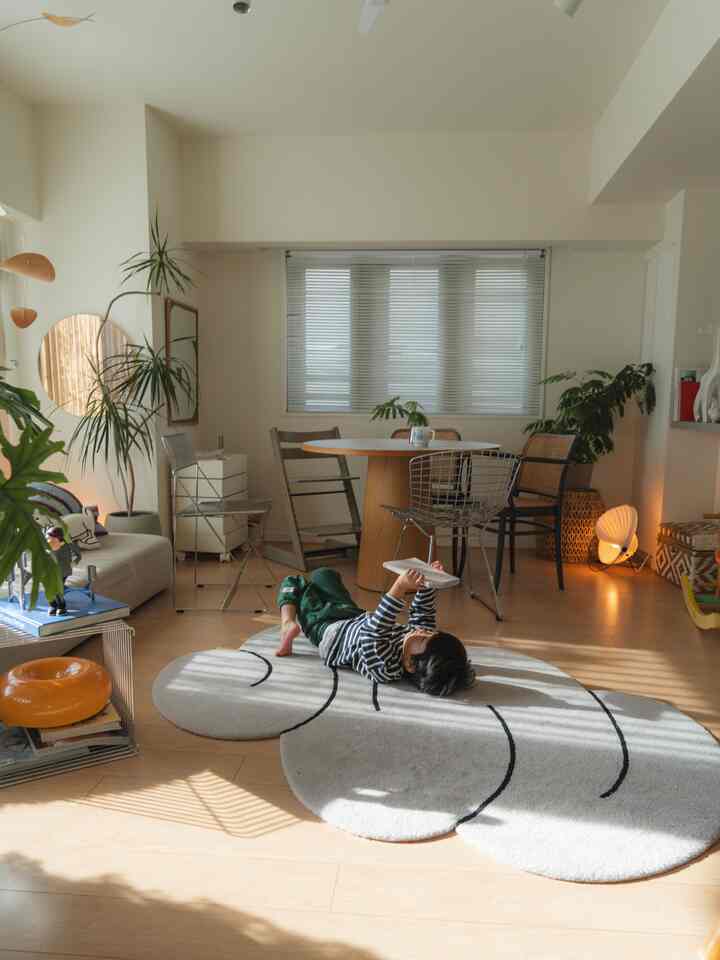 A natural modern living and dining room featuring white and wood tones, with a child comfortably lying on the rug