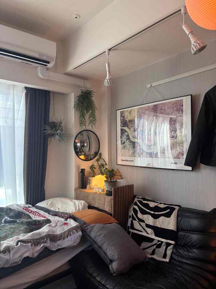 チャコールとホワイトの色調の8畳寝室、ベッドとソファが配置されたモダンで落ち着いた印象のあるインテリア